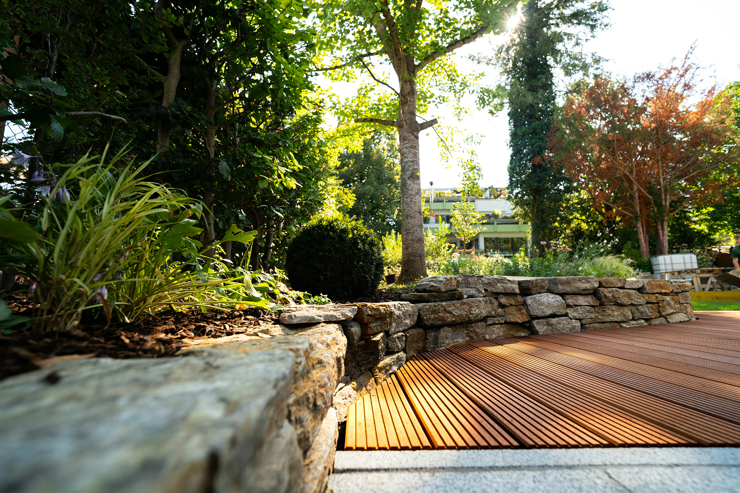 Bild einer Terrasse aus Holz mit Blumenbeet.