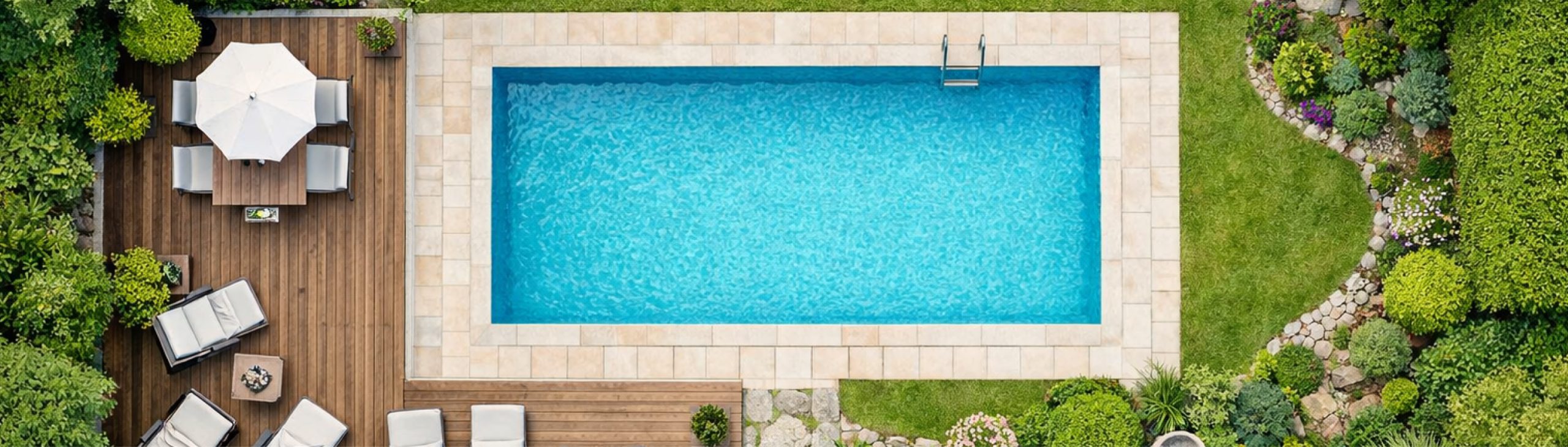 Topshot einer Fotografie von einem Pool mit Terrasse, Sonnenschirm und Liegen. Rechts befinden sich Grünflächen.