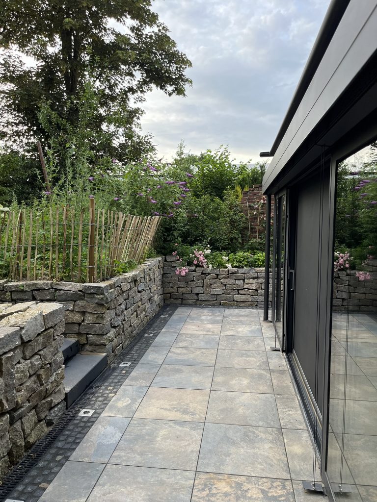 Terrasse mit Natursteinmauer.