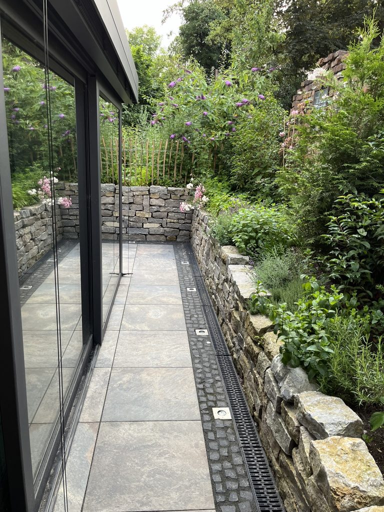 Outdoorterrasse mit Natursteinmauer.